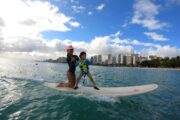 small boy and his mother riding a wave at waikiki, hawaii