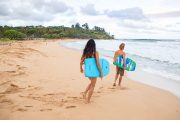 Couple head out to bodyboard in Kealia, Kauai