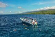 people snorkeling next to a boat along the Kona coast